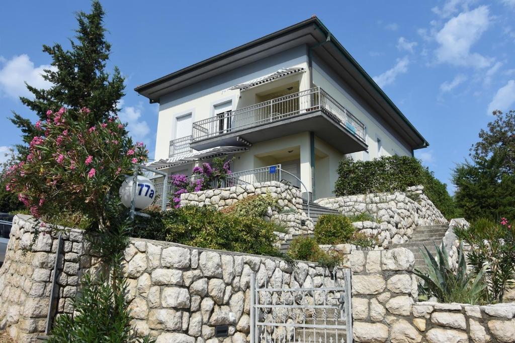 a white house on top of a stone wall at Apartments Car in Rab