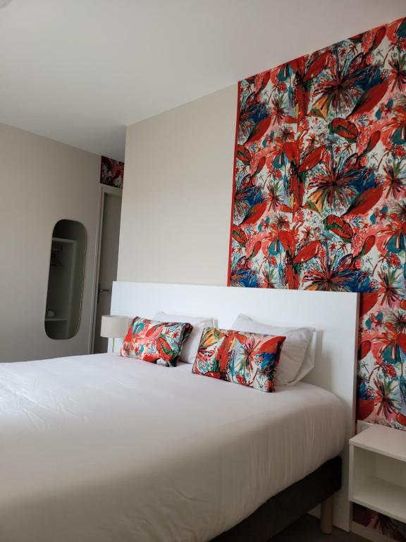 een slaapkamer met een wit bed met bloemenbehang bij Hôtel Port Haliguen in Quiberon