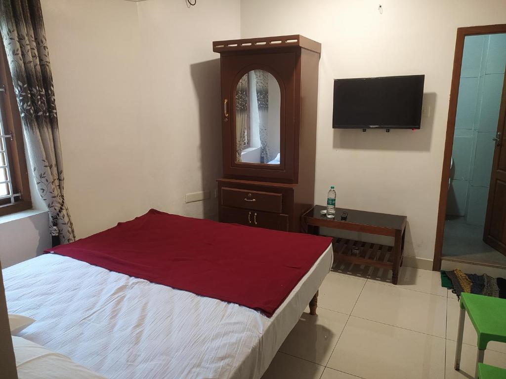 een slaapkamer met een bed, een dressoir en een tv bij Mubarak Family Restaurant in Kuzhittura