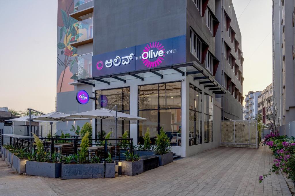 Olive Hotel Brookefield by Embassy Group في بانغالور: مطعم بطاولات ومظلات امام المبنى