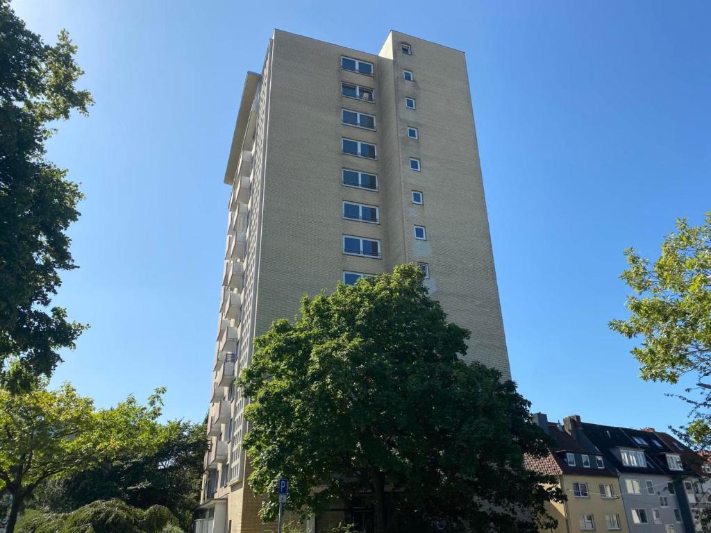 een hoog gebouw met een boom ervoor bij FEWO am Deich 1 in Bremerhaven