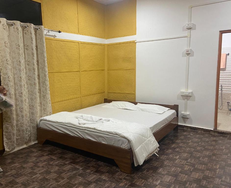 1 dormitorio con cama y pared amarilla en TULDA BAMBUSA RESORT, en Kāziranga