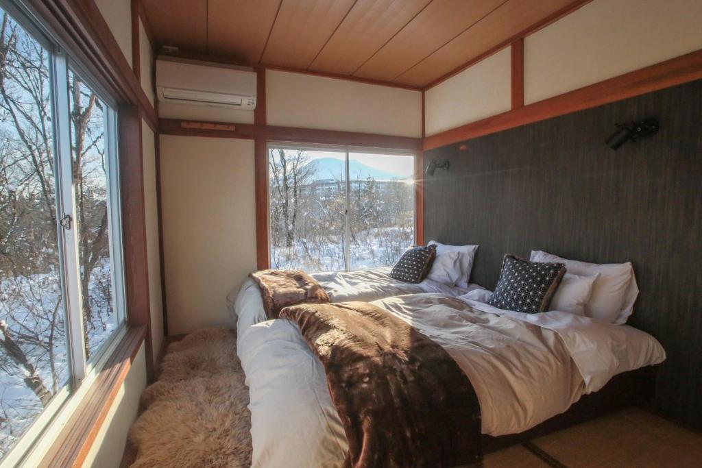 a bed in a room with a large window at Lucky Duck Cabin Myoko in Myoko