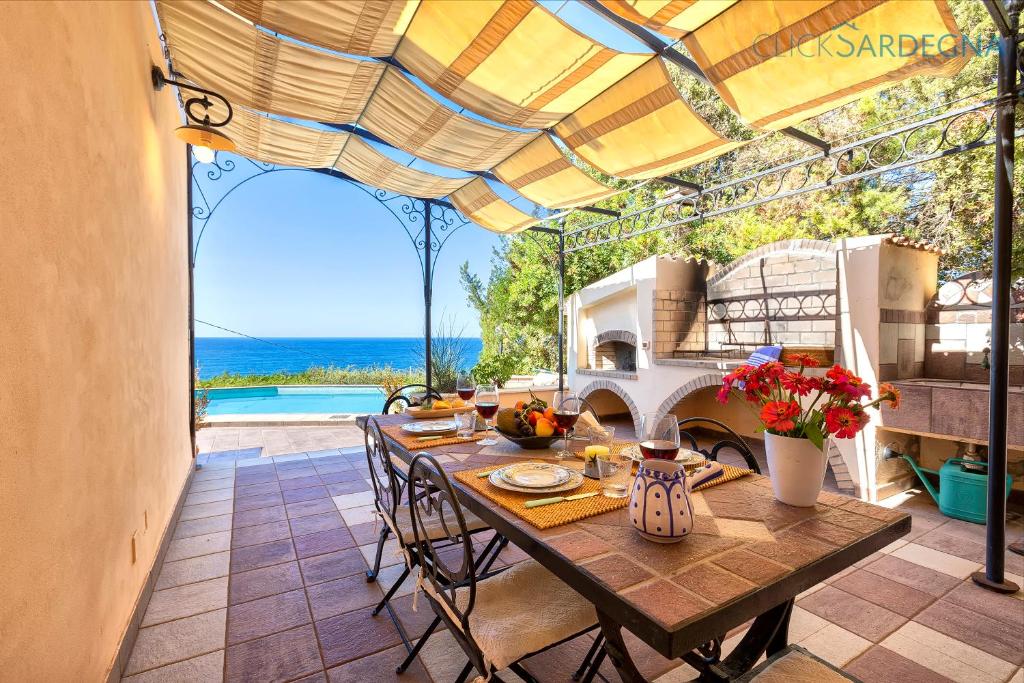 une salle à manger avec une table et une vue sur l'océan dans l'établissement Villa Joie de Vivre Vista mare con piscina a sfioro per 6 persone, à Alghero
