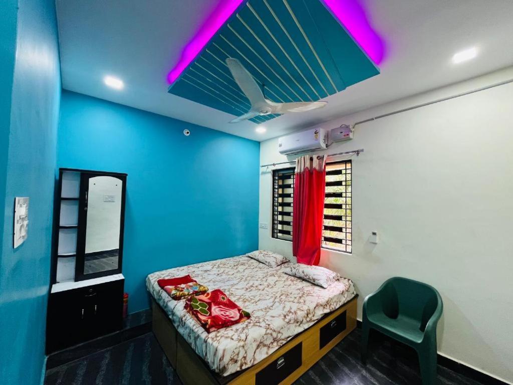 um quarto com uma cama e uma parede azul em Chaitra Home Hampi em New Hampi