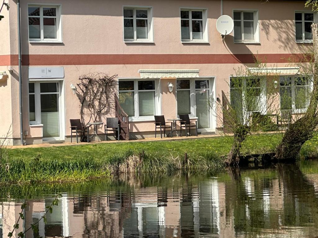 um edifício com mesas e cadeiras ao lado de uma massa de água em Waterkant em Lübz