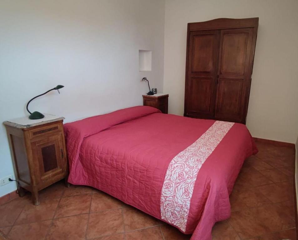 1 dormitorio con cama rosa y armario de madera en Un tuffo vintage tra mare_monti en Pianavia