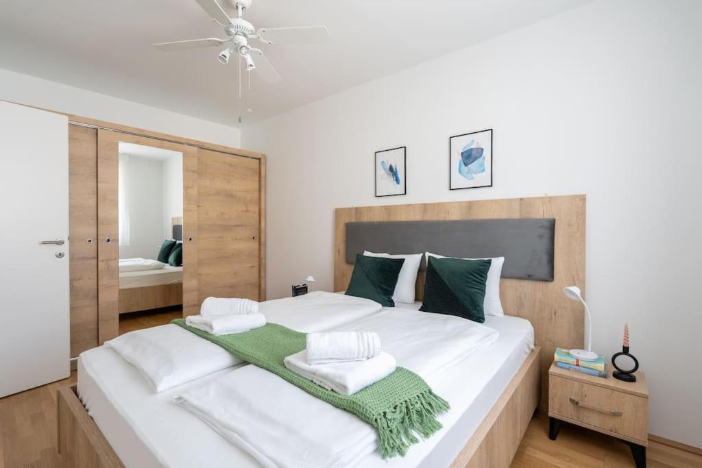 een slaapkamer met een groot wit bed en een groene deken bij HM • Trendy 1BR, Direct City Access in Wenen