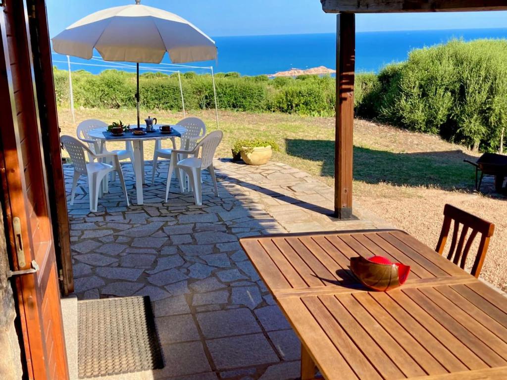 un patio con mesa, sillas y sombrilla en Le Verande di Isola Rossa, en Isola Rossa