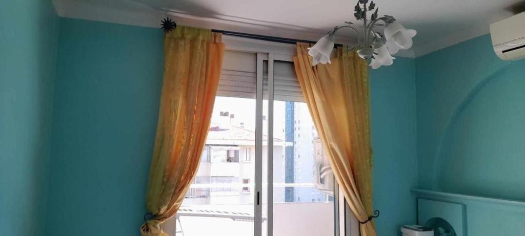 Cette chambre dispose d'une fenêtre avec des rideaux orange. dans l'établissement Chambre privée et climatisée dans un appartement de 4 chambres, à Toulon