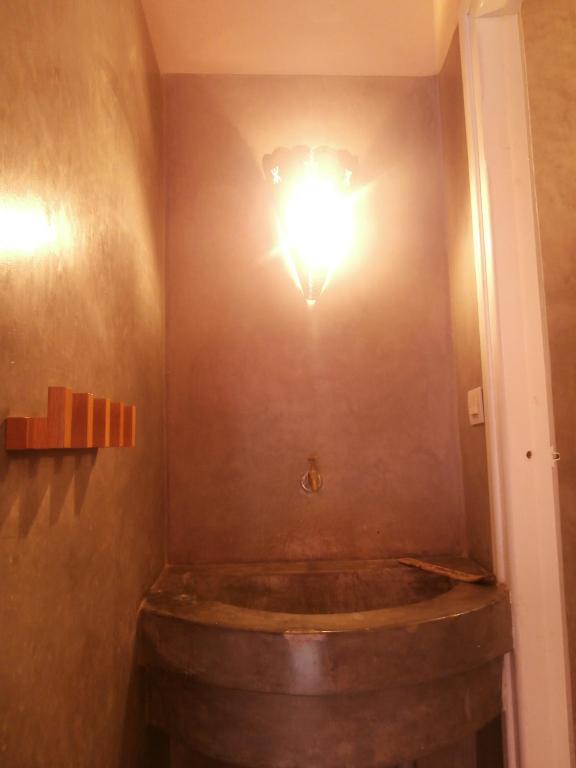 a bathroom with a light on the wall and a large wine barrel at Maison Xanadu in Sidi Ifni
