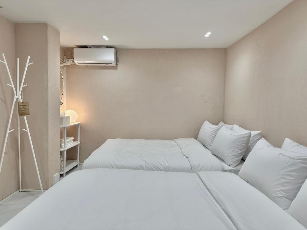 een slaapkamer met 2 bedden en witte kussens bij hoho house - double twin room in Busan