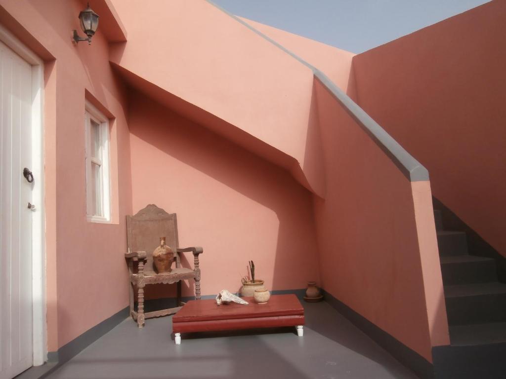 a room with a staircase with pink walls and a red ottoman at Maison Xanadu in Sidi Ifni