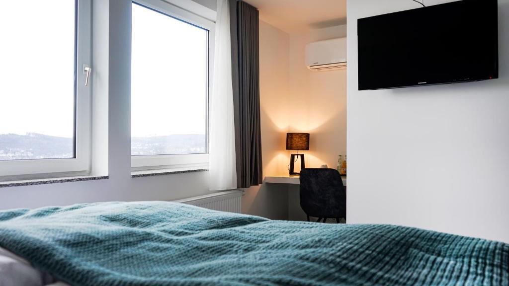 1 dormitorio con 1 cama y TV de pantalla plana en SI-View Doppelzimmer mit Stadtblick Zimmer 21, en Siegen