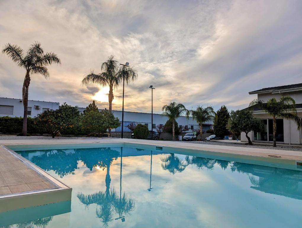 a swimming pool with palm trees and a cloudy sky at Villa Dafne in Torrenova
