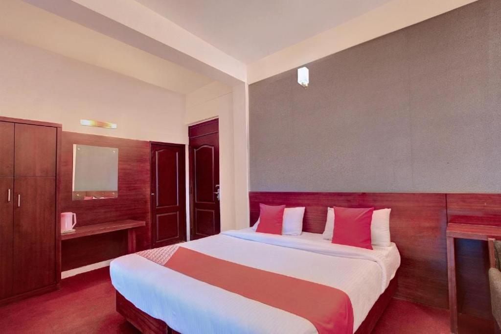 a bedroom with a large bed with red and white pillows at Ooty Residency in Ooty