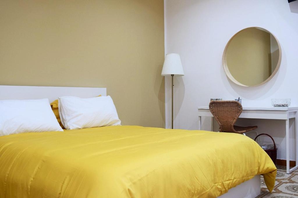 een slaapkamer met een geel bed en een spiegel bij La Perla in Isola delle Femmine