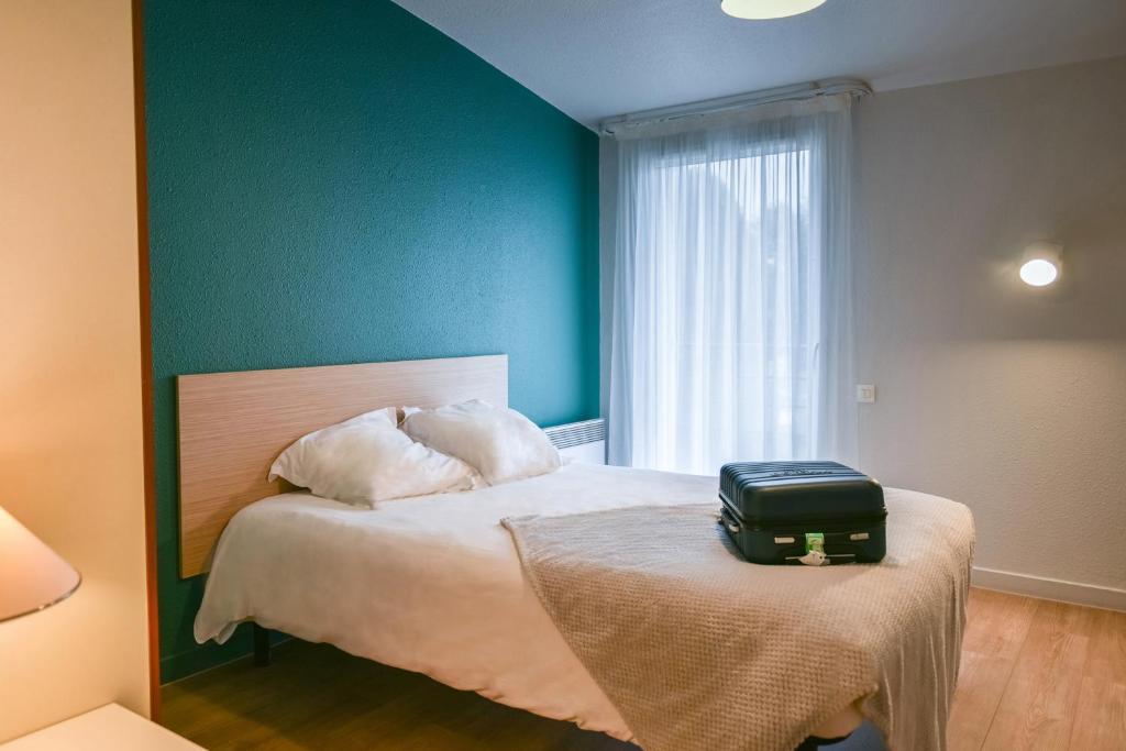 - une chambre avec un lit et une valise sur une table dans l'établissement Terres de France Brest, à Brest