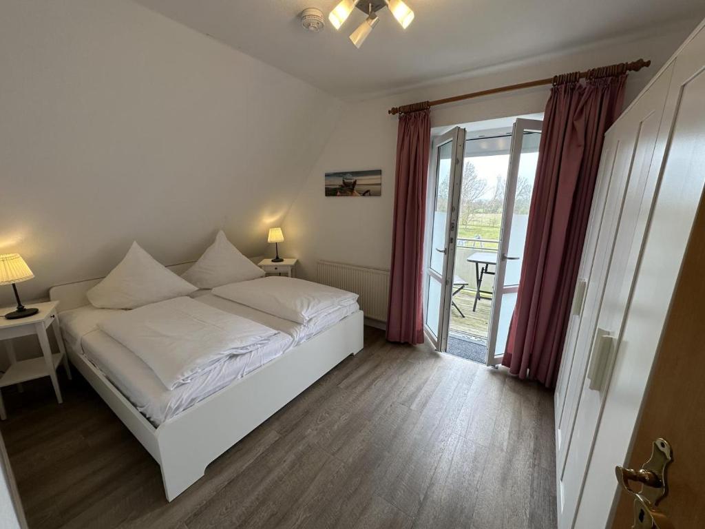 a bedroom with a white bed and a balcony at Fehmarn 17-2 in Fehmarn
