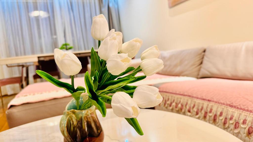 eine Vase voller weißer Blumen auf dem Tisch in der Unterkunft Sweet home near Paris with Eiffel Tower view & 1 cozy private room or entire apartment with 3 rooms in Courbevoie