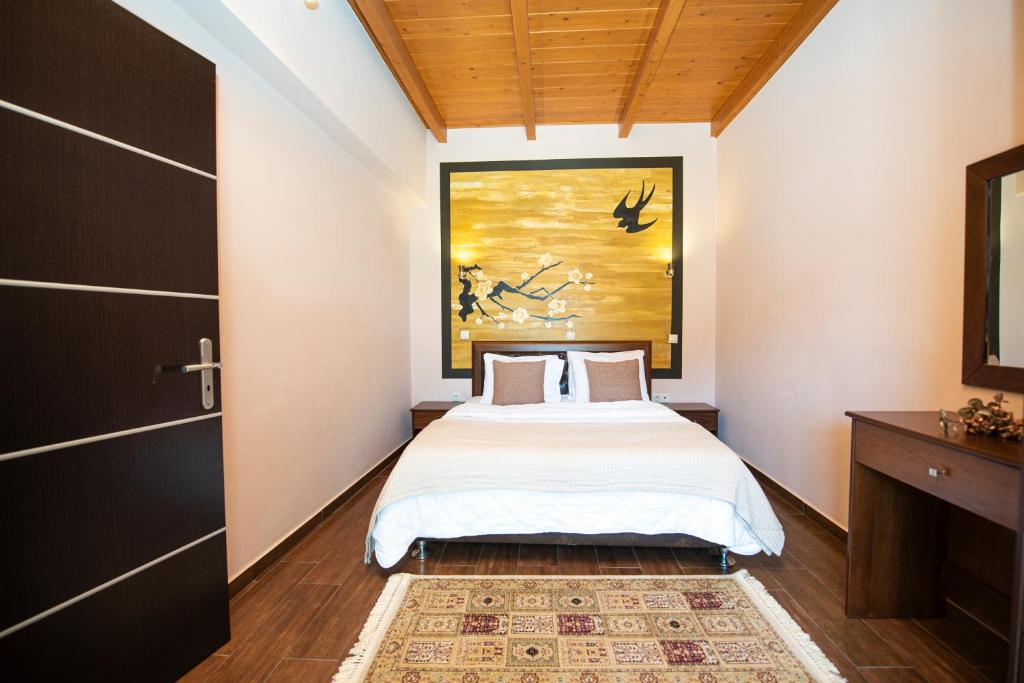 a bedroom with a bed and a painting on the wall at Ostrella Hotel - Luxury rooms in Mýtikas