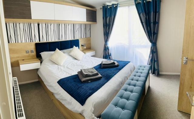 a bedroom with a large bed with a blue tufted bedskirts at Bull Rush Retreats luxury hot tub lodge at Tattershall Lakes in Tattershall