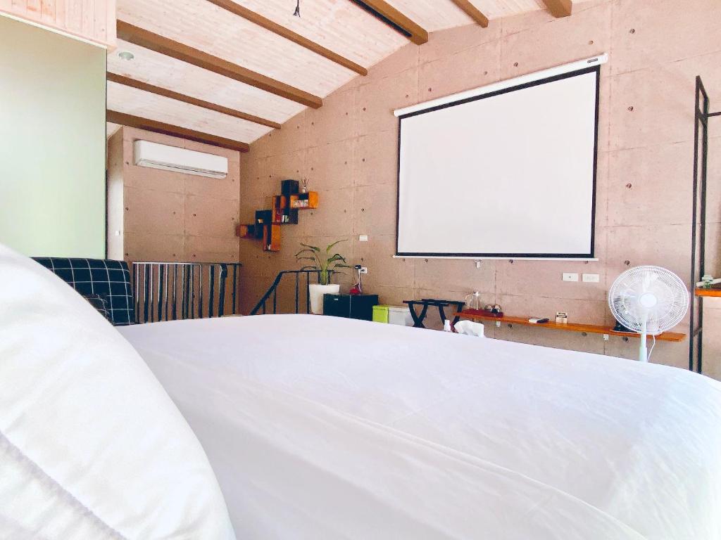 1 dormitorio con cama blanca y pantalla de proyector blanca en 辣虎邸家 Love Here en Tainan