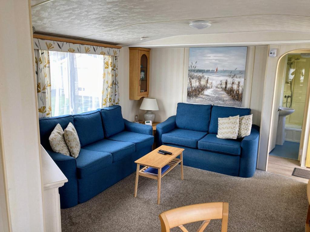 a living room with blue couches and a table at Sea Breeze at Winthorpe Skegness in Skegness