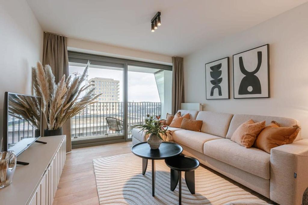 a living room with a couch and a table at Modern apartment close to the beach with common pool in Ostend