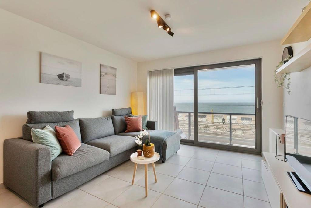 a living room with a couch and a view of the ocean at Cosy apartment with amazing beach view in Ostend