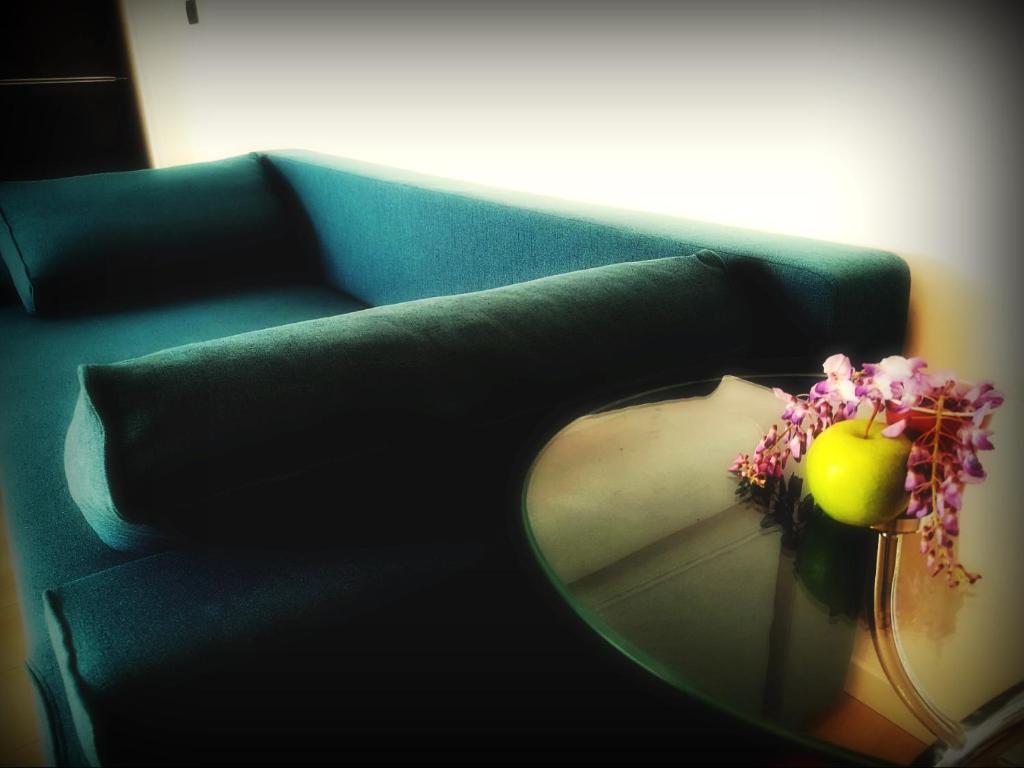 a green couch with a glass table and a vase with flowers at AURORA suites in Ghiroda