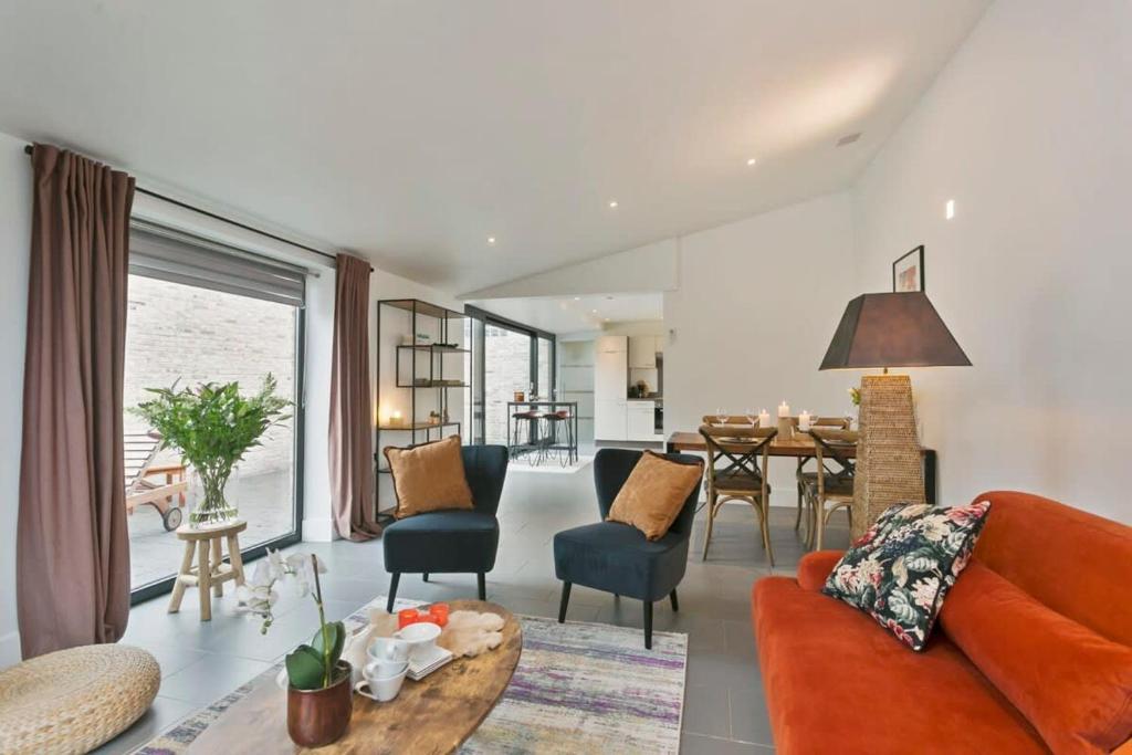 a living room with an orange couch and a dining room at Charming house in the beautiful village Donk with a terrace in Maldegem