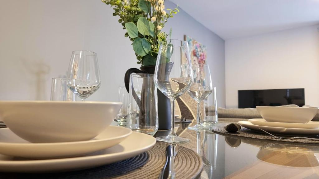 einen Tisch mit Tellern und Gläsern und eine Vase mit Blumen in der Unterkunft No.62 Fivedom - Luxury apartment in Southampton