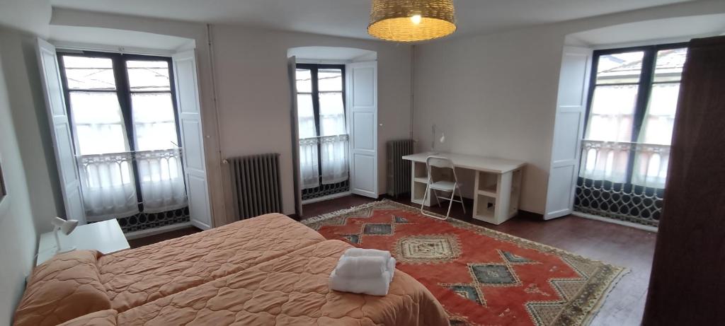 Un dormitorio con una cama, un escritorio y ventanas. en PISO CON TERRAZA, en Ribadeo