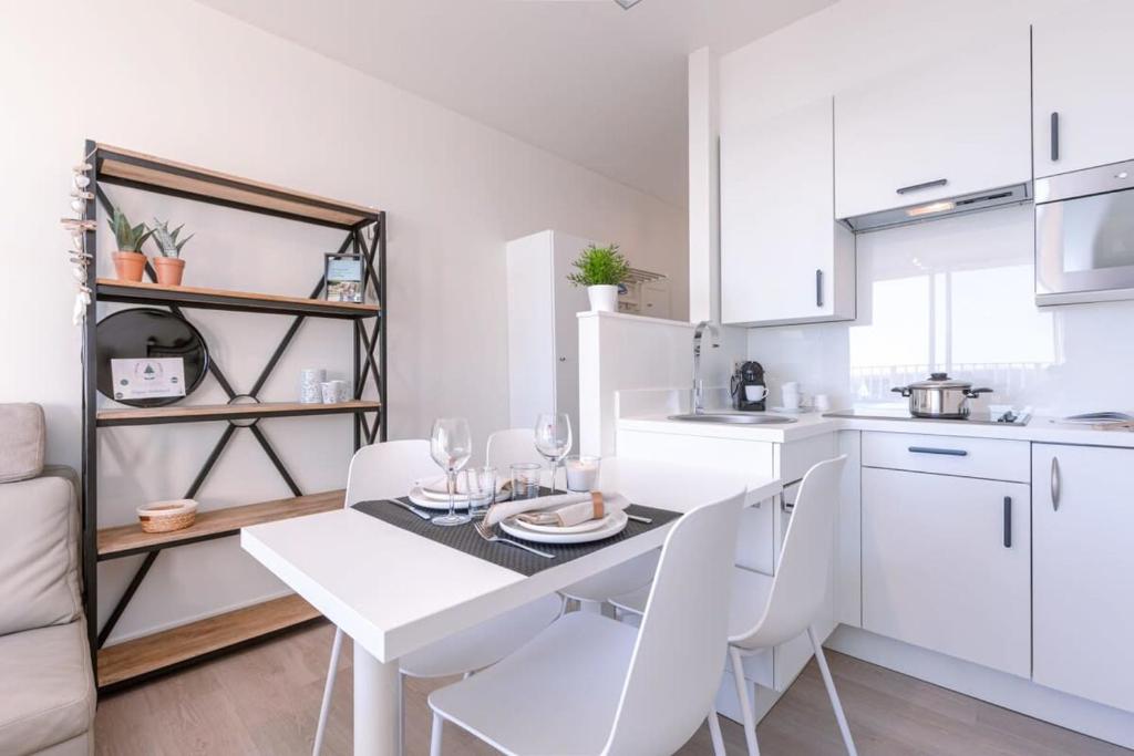 cocina blanca con mesa blanca y sillas blancas en Huswell - Modern studio near the sea and beach, en Nieuwpoort