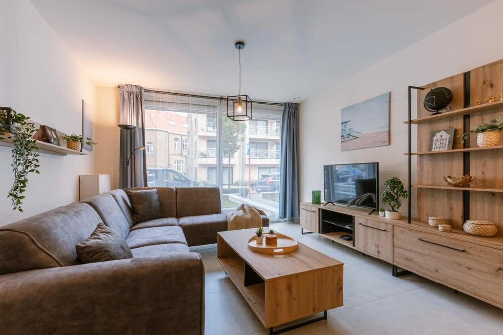 een woonkamer met een bank en een tv bij Bright apartment only 5 minutes from the beach in Middelkerke