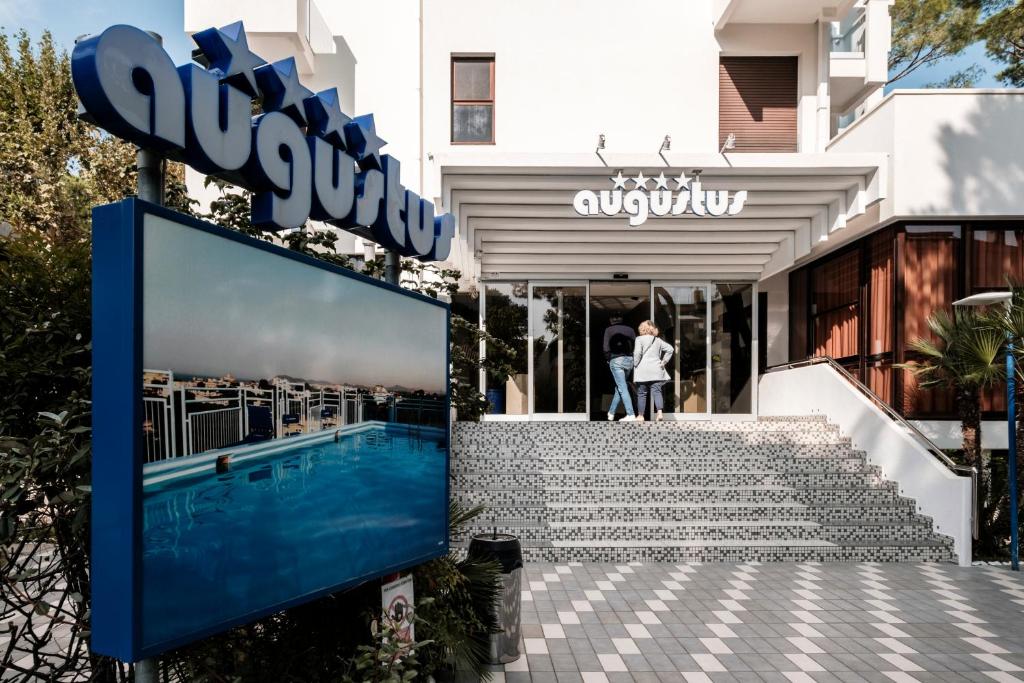 una facciata di un edificio con un cartello e una piscina di Augustus Hotel Riccione Centro a Riccione