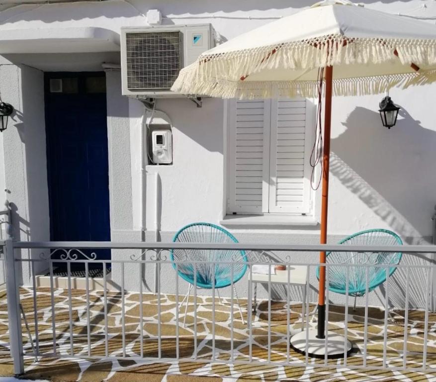 un patio con 2 sillas y una sombrilla en Casa by Hokkum Studios, en Kokkari