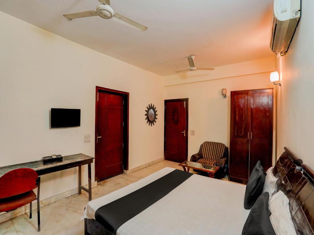 a bedroom with a bed and a desk and a tv at Super OYO Le Regent in Gurgaon