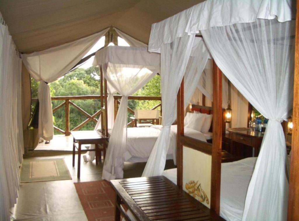 sunshine maasai Mara safari camp in Kenya في Sekenani: غرفة نوم بسريرين وشرفة