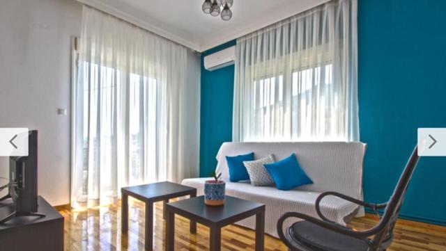 a living room with a white couch and blue walls at Cosy Colorful House with Private Parking in Kavála