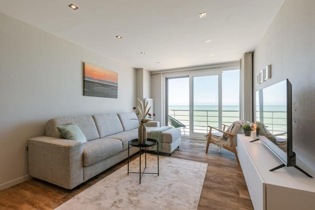 a living room with a couch and a large window at Cosy apartment with frontal seaview in Nieuwpoort