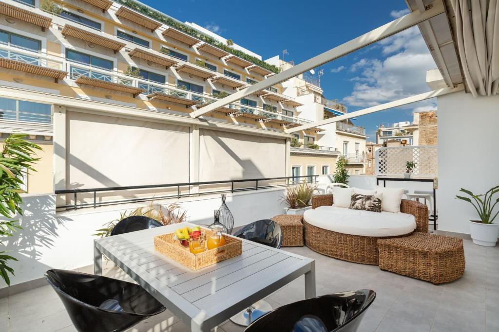 a patio with a table and chairs on a balcony at OPEN SKIES- PENTHOUSE IN PLAKA- ACROPOLIS VIEW! in Athens