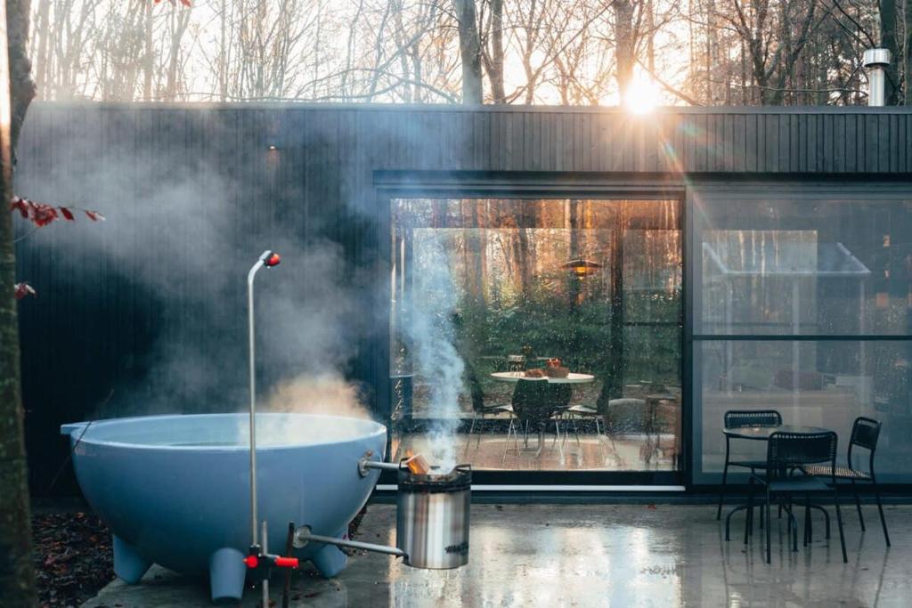 a bath tub on a patio with smoke coming out of it at Cabin in the woods with hottub in Stekene