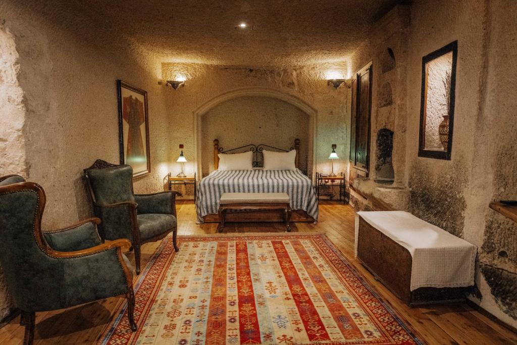 1 dormitorio con 1 cama, 1 silla y 1 alfombra en Aza Cave Cappadocia Adult Hotel, en Göreme