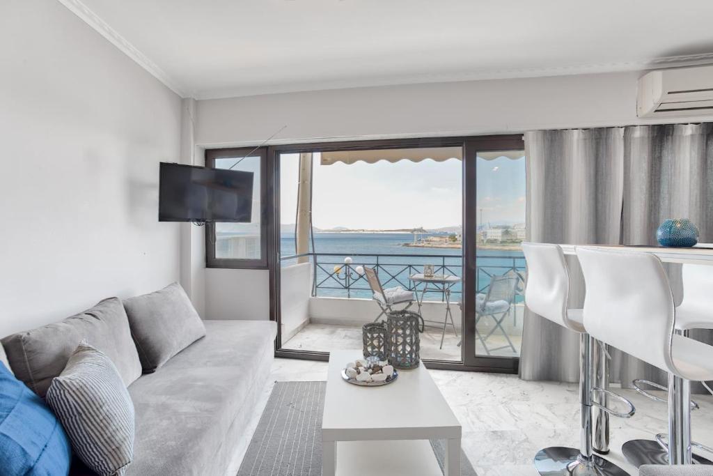 a living room with a couch and a view of the ocean at Chic, Modern Seaside Oasis in Sunny Piraeus! in Piraeus