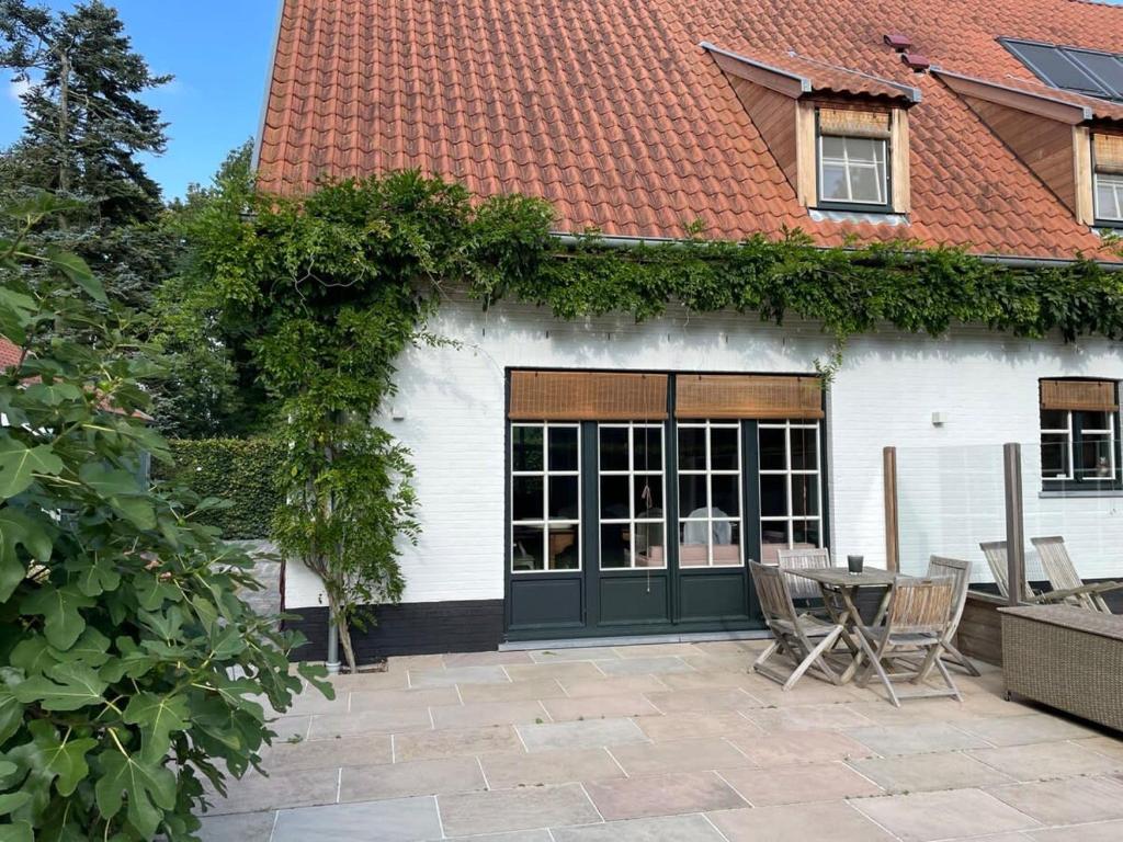 a house with a table and chairs in front of it at Two guest-rooms in stylish villa - free bikes in Bruges