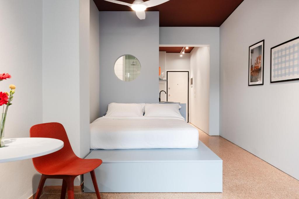 une chambre avec un lit blanc et une chaise rouge dans l'établissement Acre Urban Studios in Monastiraki, à Athènes