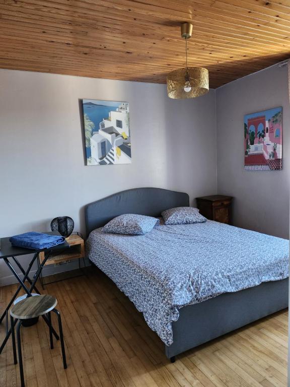 - une chambre avec un lit bleu et un plafond en bois dans l'établissement la chambre d'Axelle, à La Bachellerie
