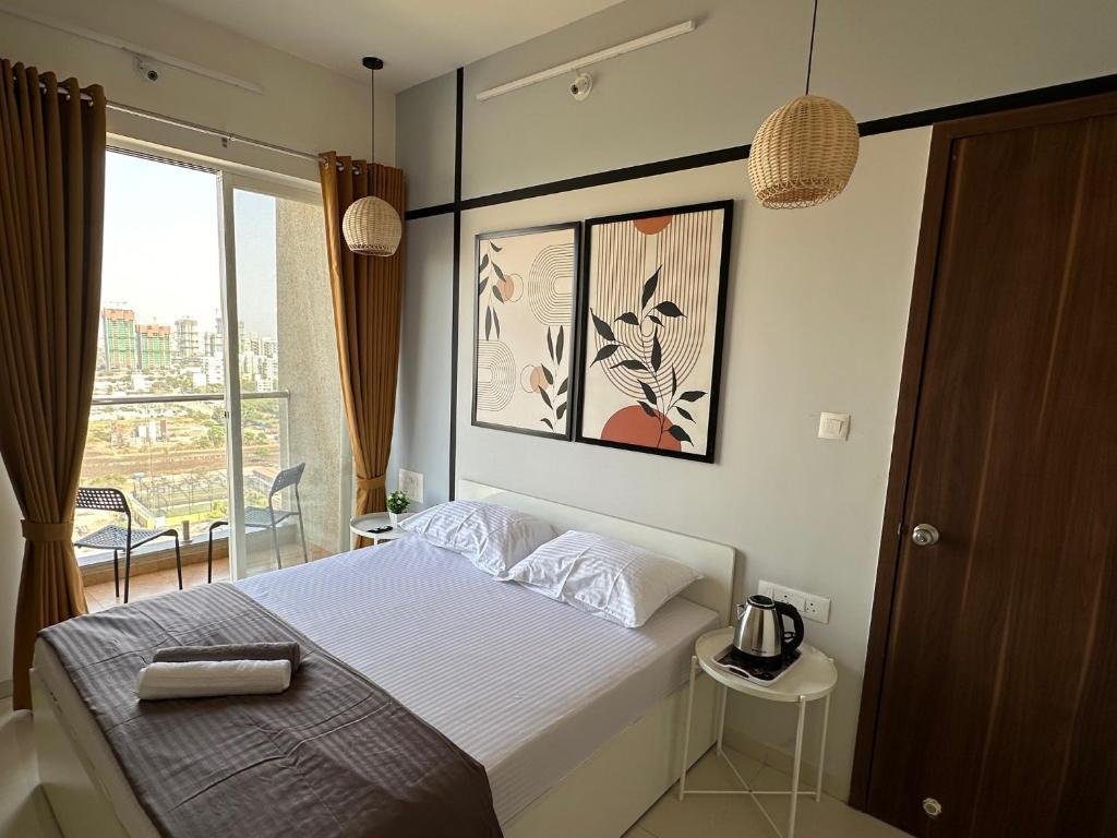 um quarto com uma cama e uma grande janela em Sky: Soothing Oasis near Balewadi High Street em Pune